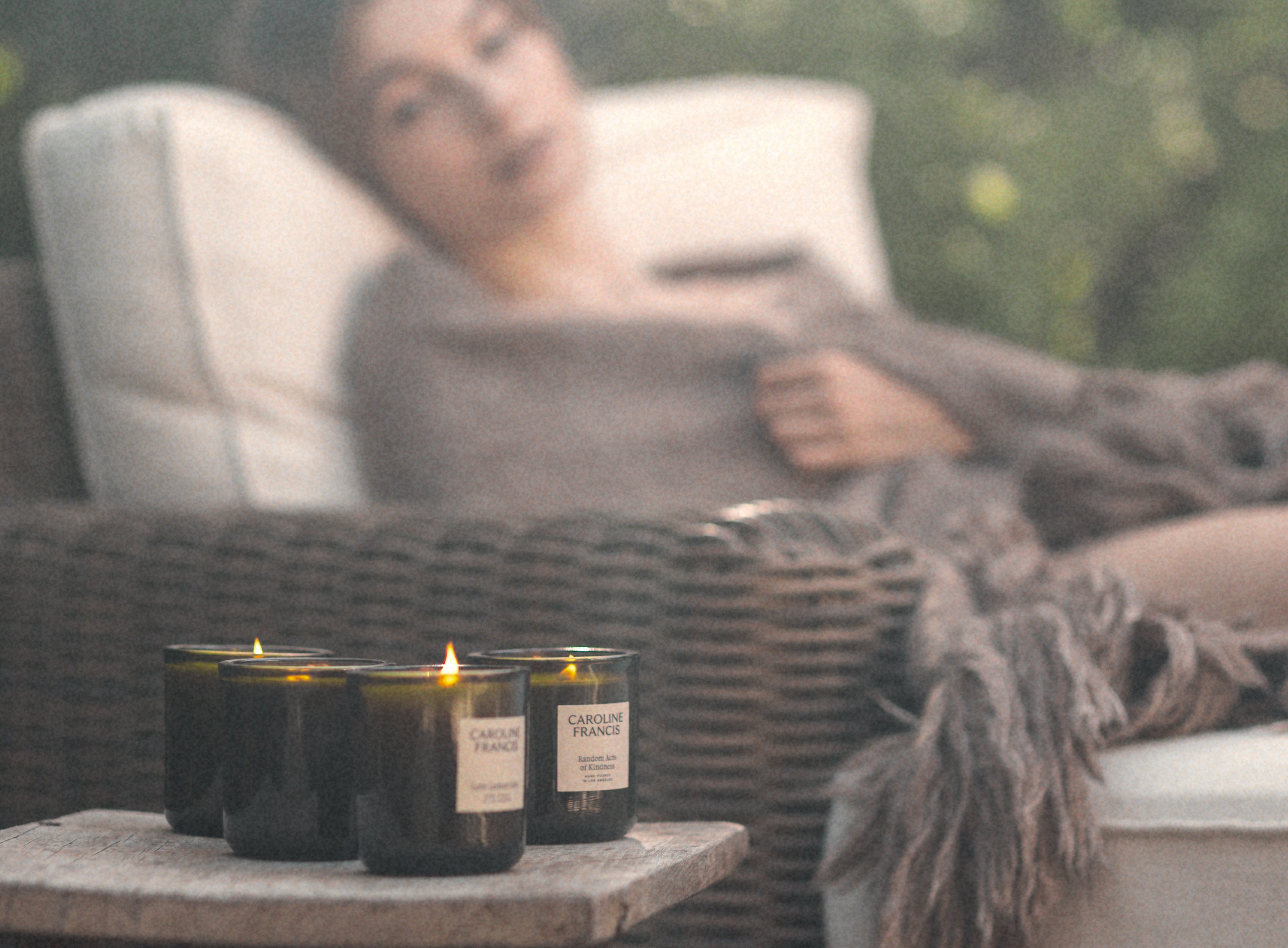 Caroline Francis candles burning on a table beside a person relaxing outdoors