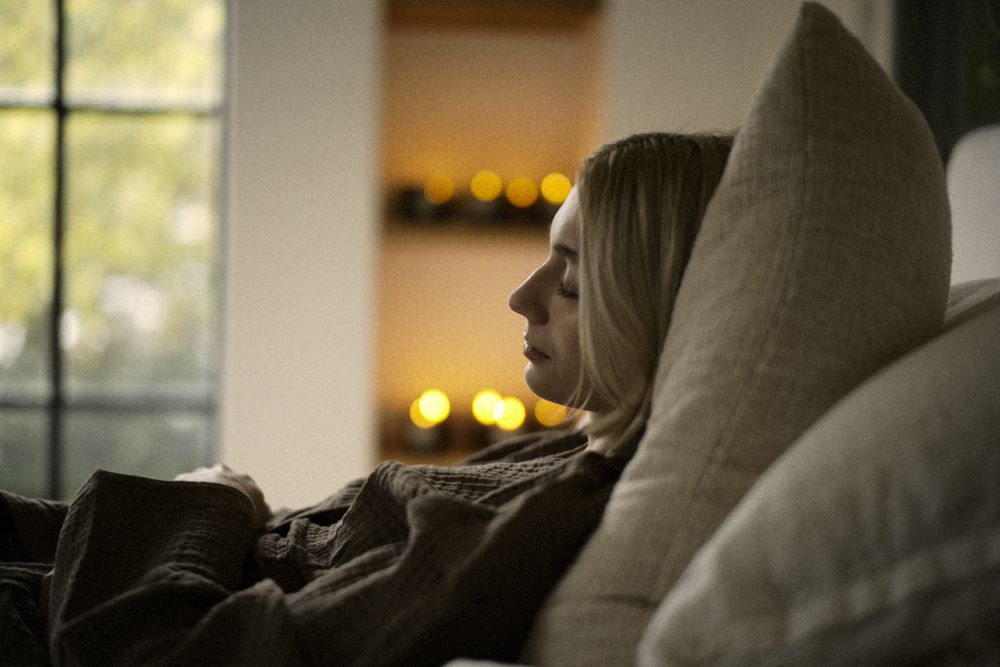 Woman Lying in Bed with Candles Burning Beside