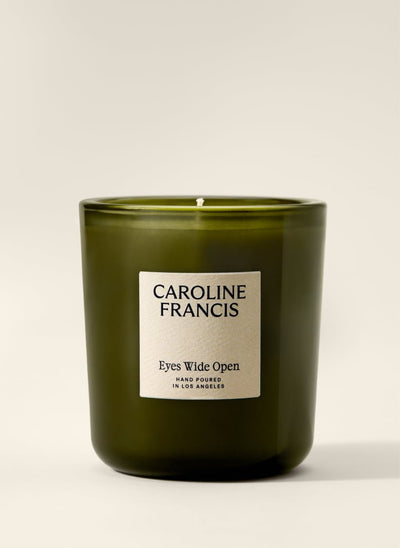 A Caroline Francis candle in an olive green glass jar with a cream-colored label, set against a plain light beige background.